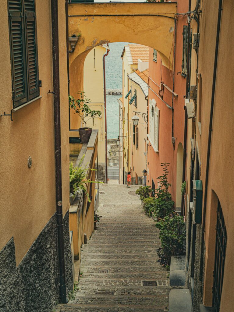 A picturesque view down a narrow alleyway leading to the sea in a historic coastal village.